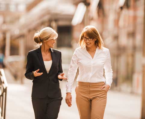 Two business women walking down street talking